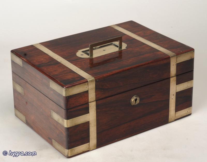 JB216: A Regency figured rosewood box with rounded edges, all brassbound, with liftout tray, document wallet, and mirror; the box having a countersunk carrying handle to the top,  and working lock and key. circa 1830. Enlarge Picture